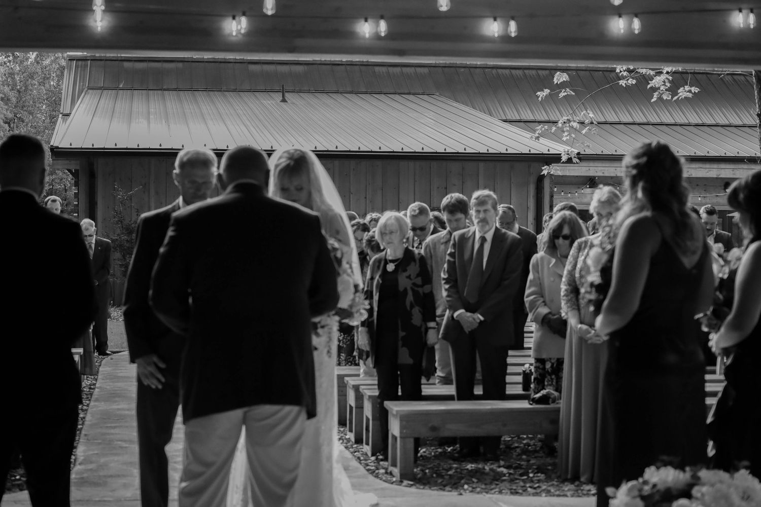 Wedding reception guests enjoying an elegant black and white celebration with string lights overhead.