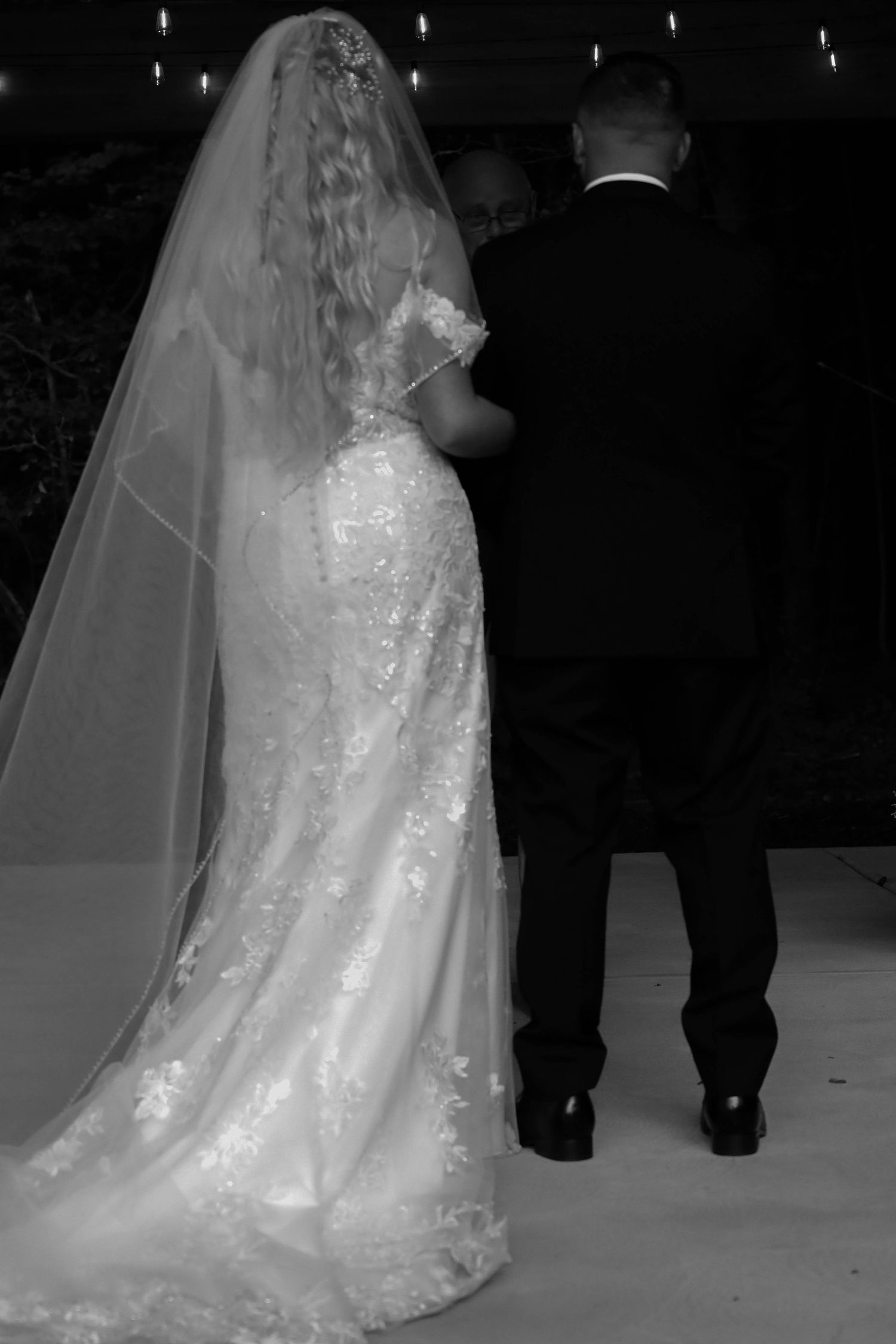 Black and white wedding dress detail shots showing the intricate lace and flowing train of a bridal gown.
