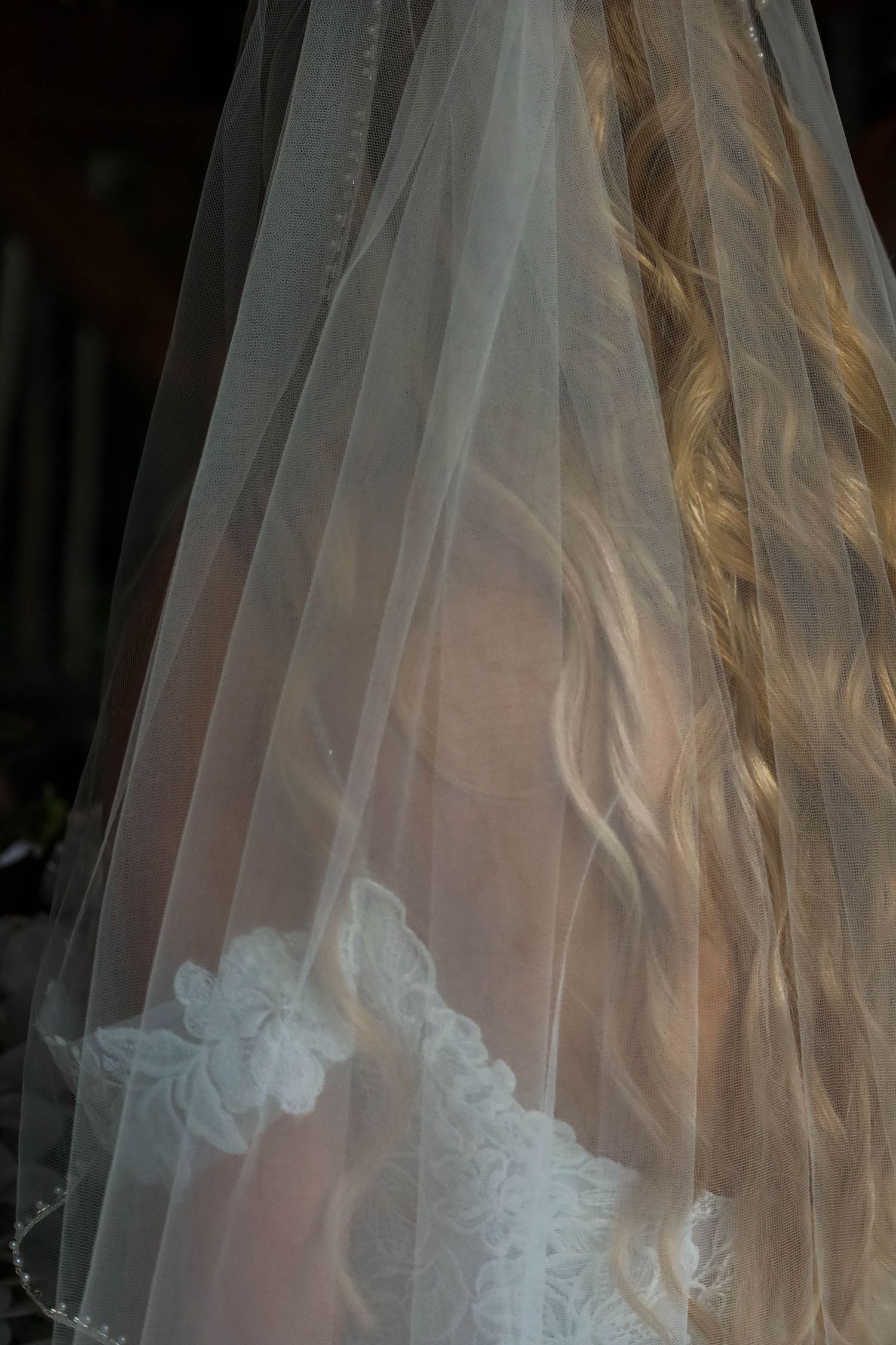 Close-up details of delicate white lace and tulle on a wedding veil at a ceremony.