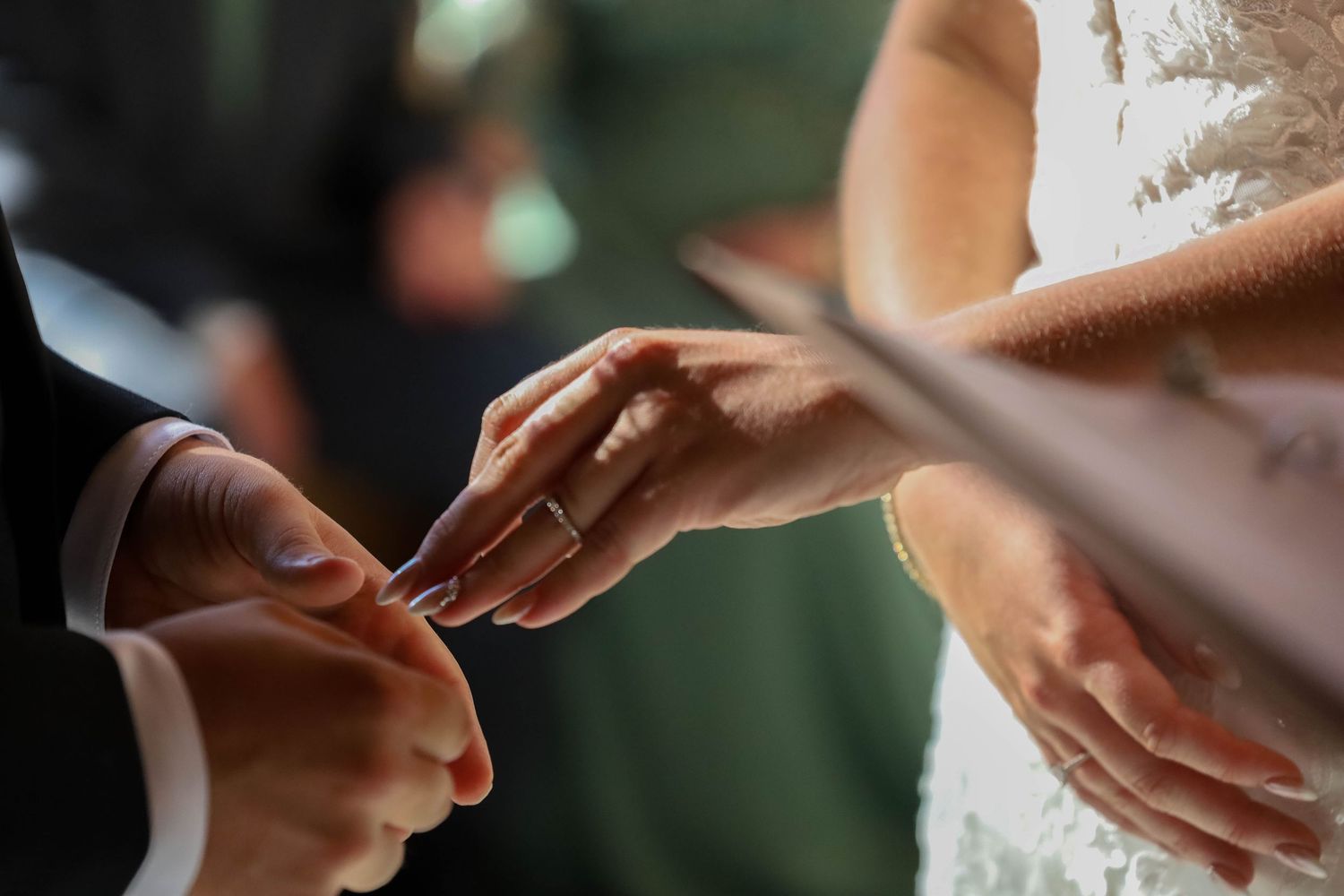 Close-up shot of bride and groom exchanging wedding rings during ceremony.
