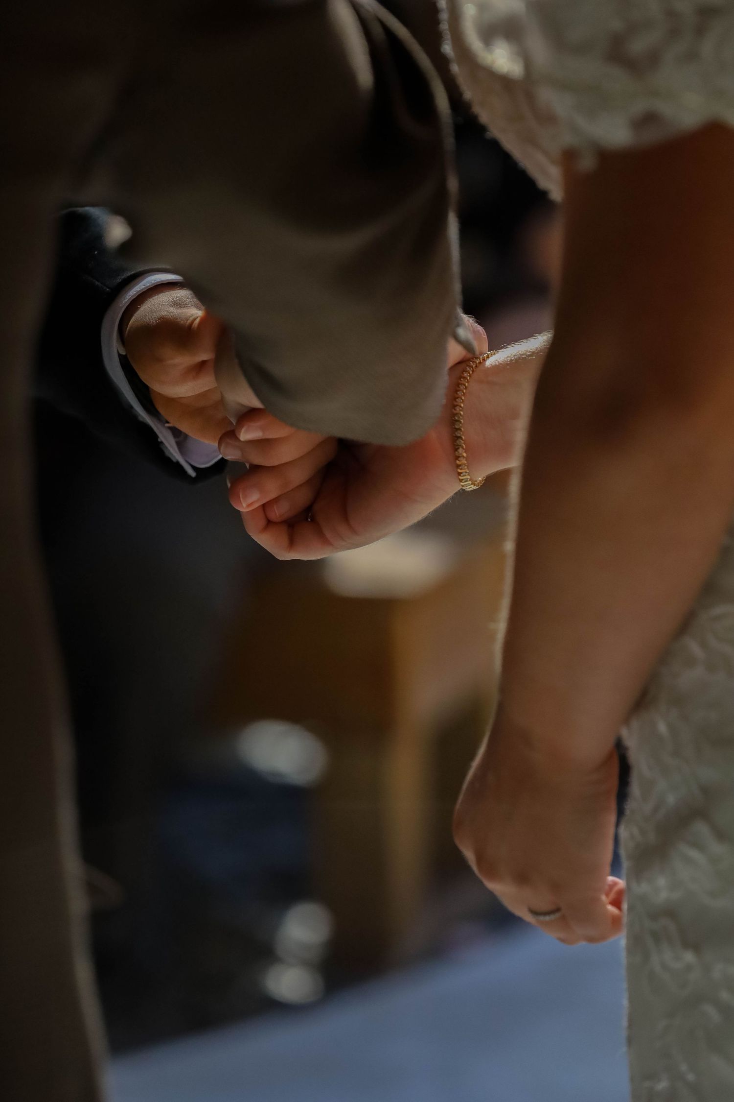 Close-up shot of two hands holding each other against dark background with soft lighting.