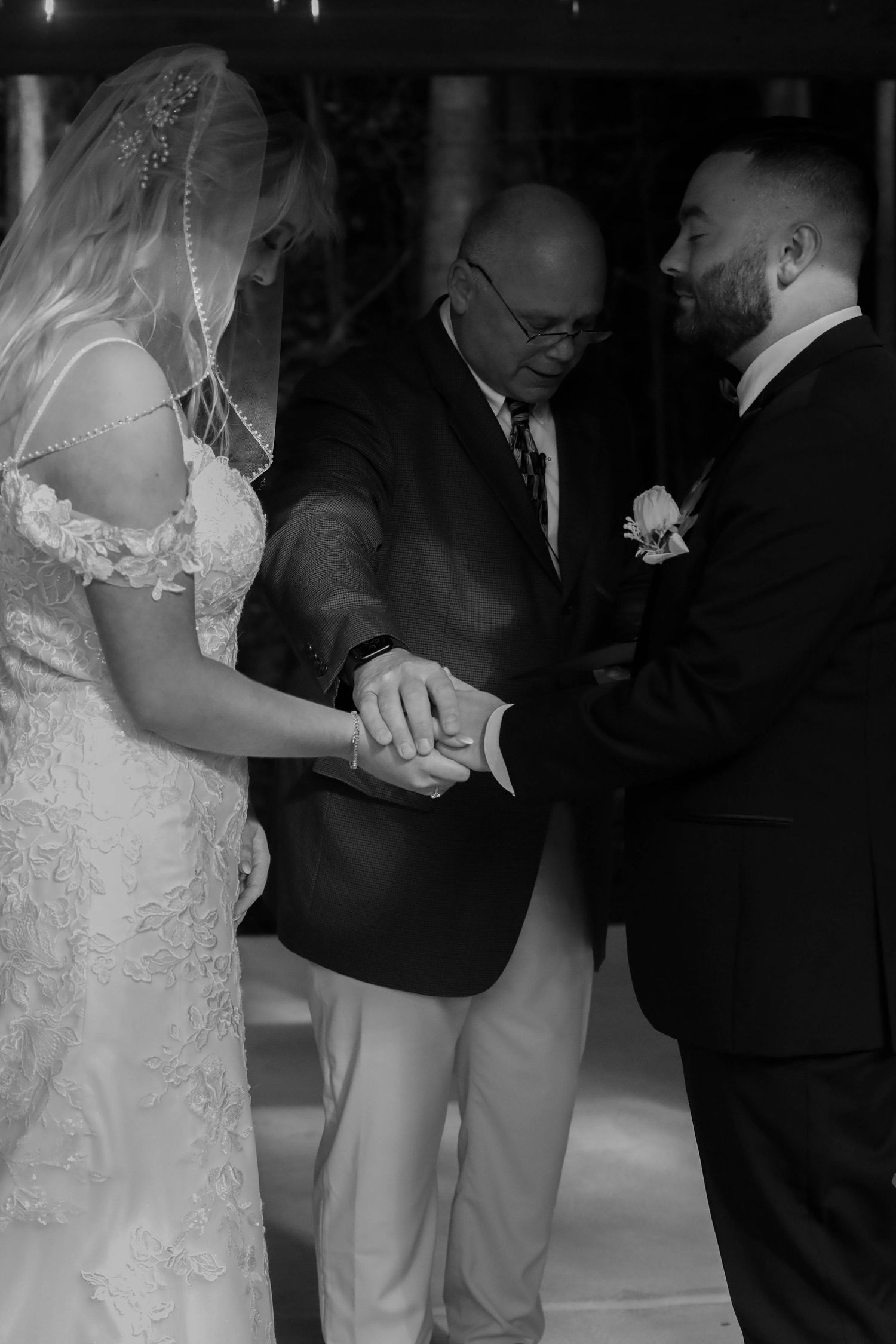 Newlywed couple in formal attire dance together during their first dance at wedding reception.