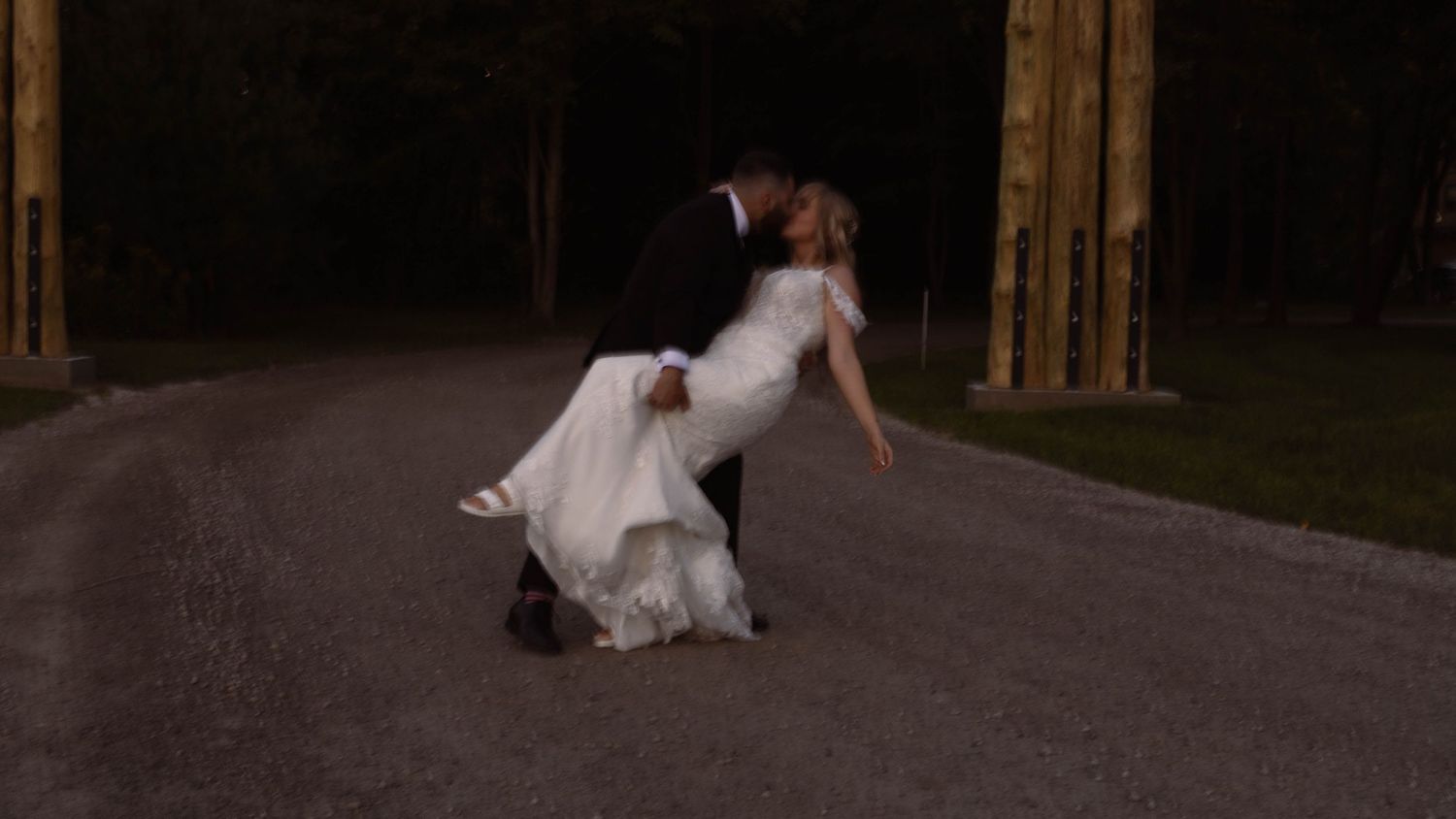 Dramatic dip pose of newlyweds dancing on a dark rural road at night.