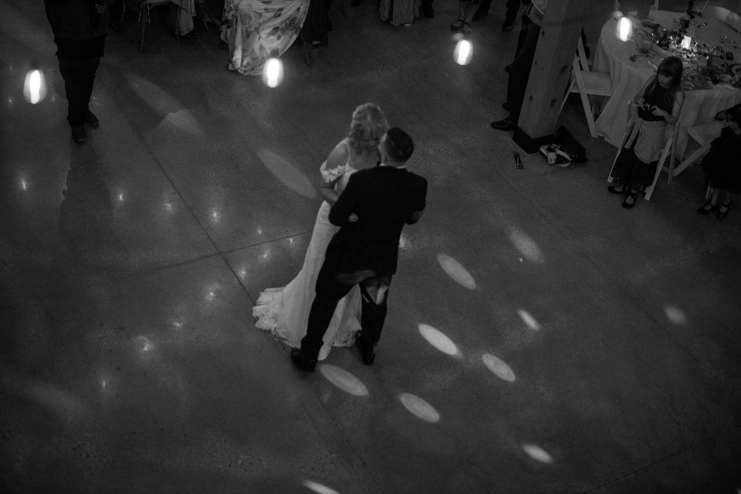 Monochrome view of dimly lit dance floor with scattered light spots creating atmospheric ambiance.