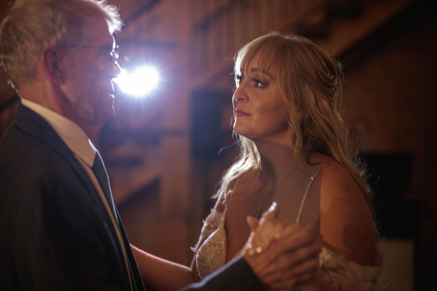 A couple shares an intimate dance moment together under dramatic lighting at an evening event.