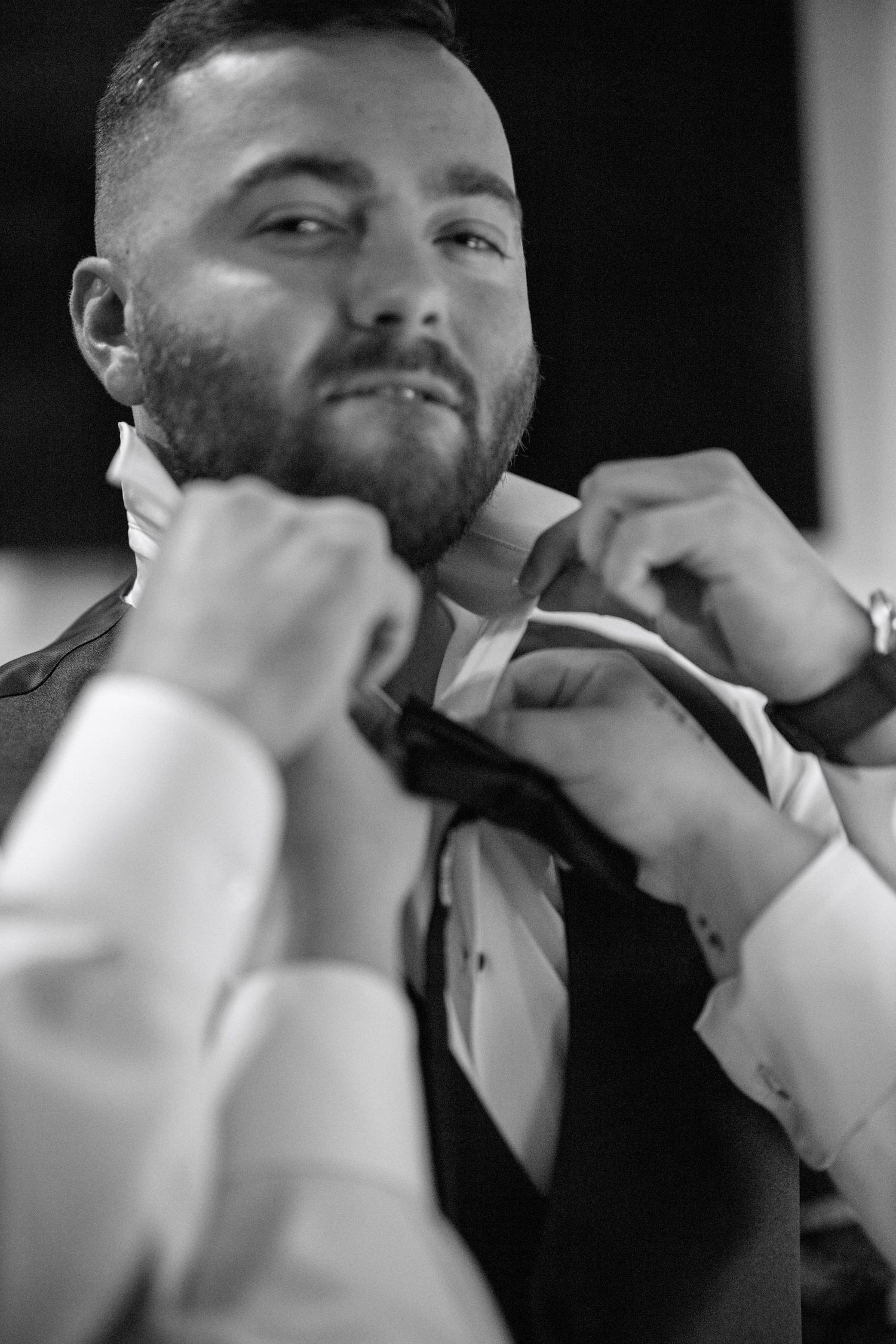 Black and white sequence of groom adjusting bowtie before wedding ceremony.