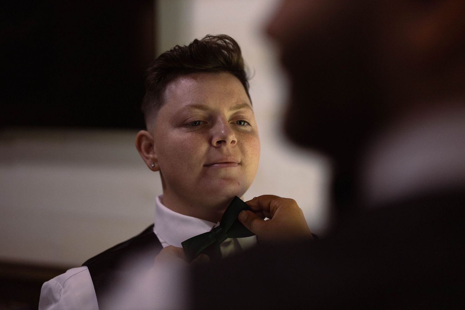 Person adjusting black bowtie while getting ready for formal event.