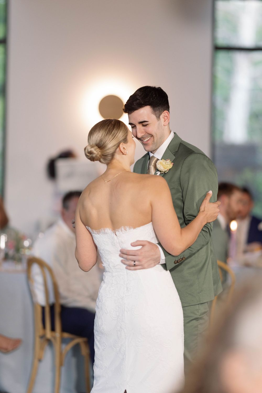 A couple shares their first dance at a wedding reception in an elegant bright venue with white decor.