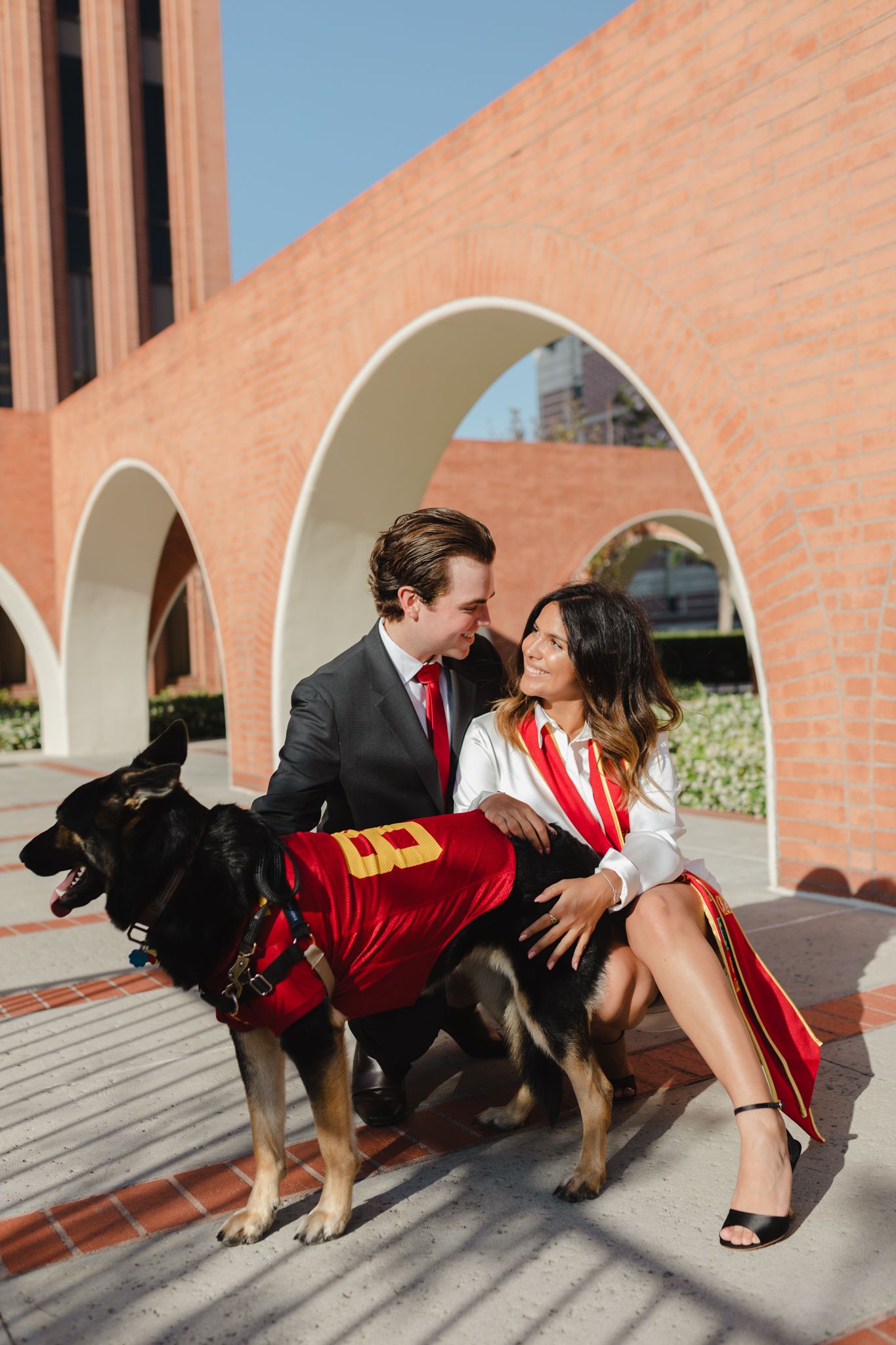 A couple with their dog take photos for their group graduation photoshoot.