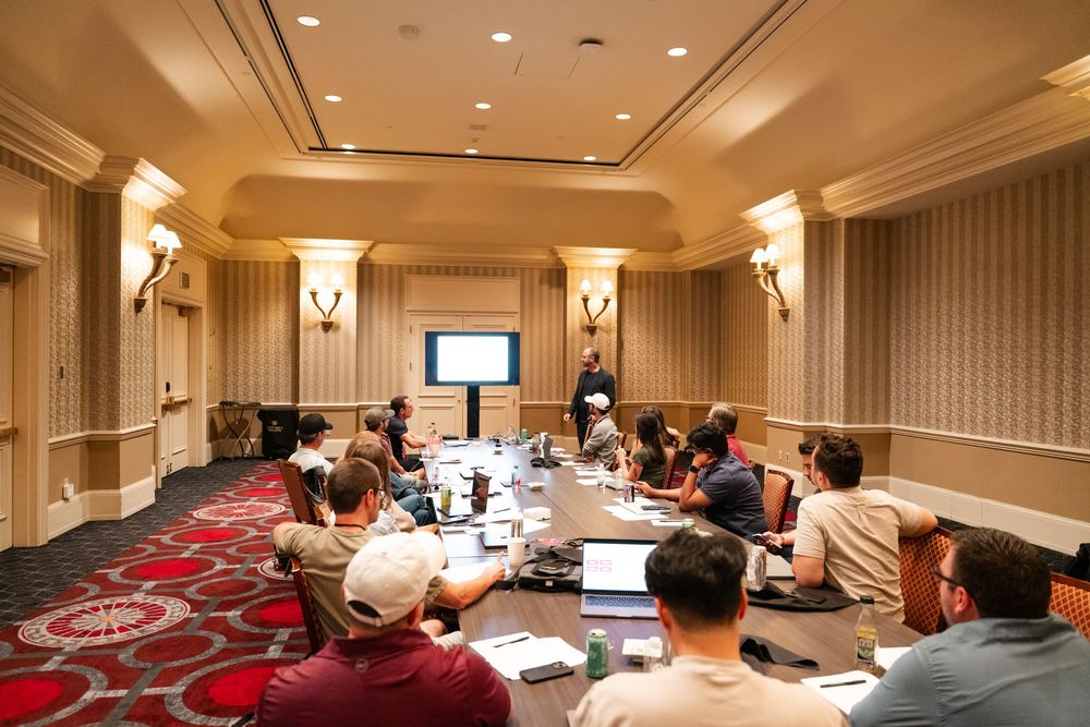 Business professionals seated around conference tables during a corporate meeting in an elegant hotel meeting room.