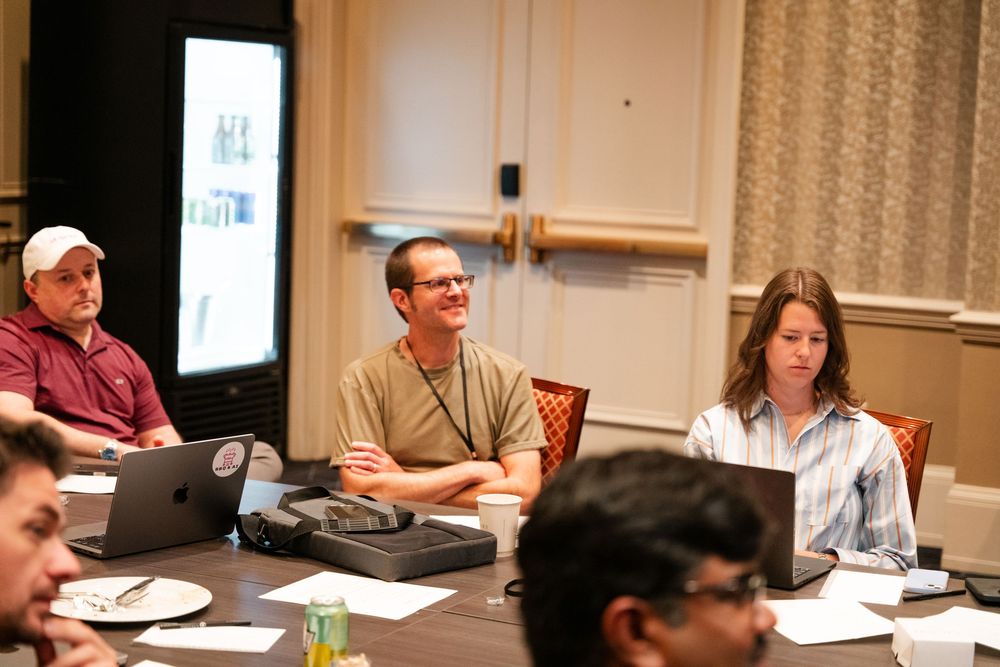 People sit at tables in a conference room during a business meeting or training session.