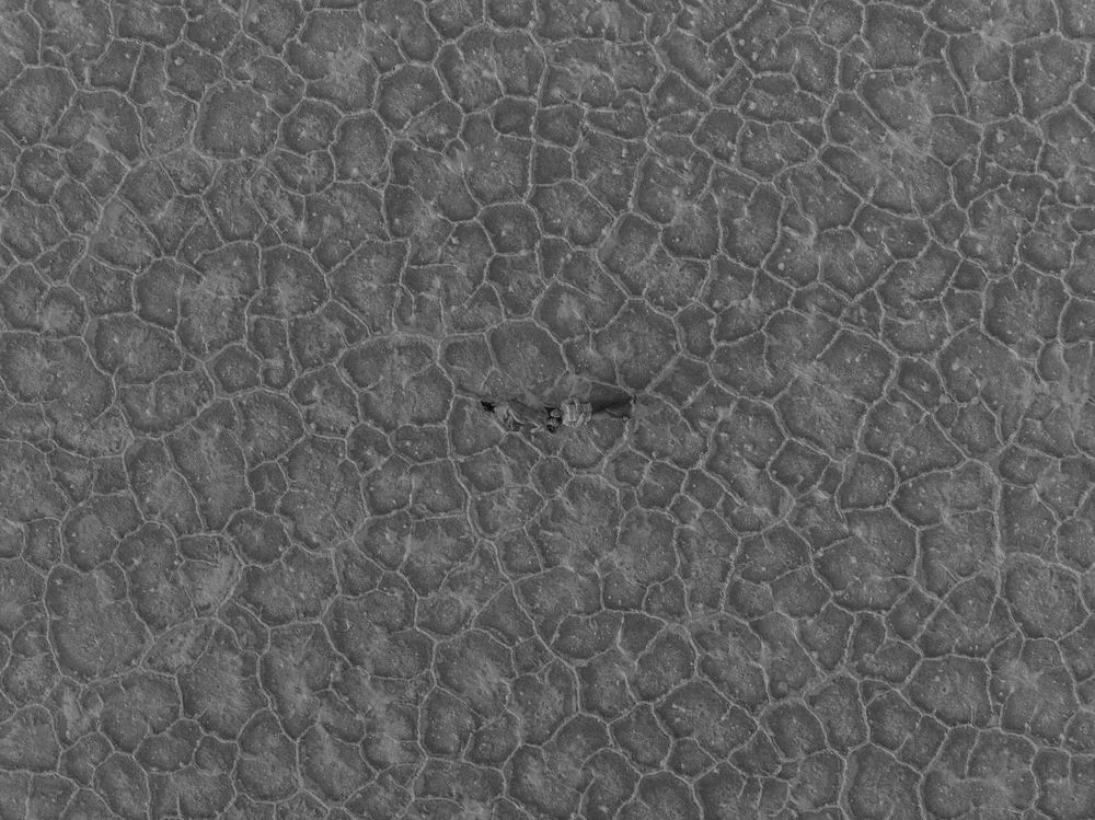 Aerial view of dried cracked mud patterns forming geometric shapes in a desert landscape.