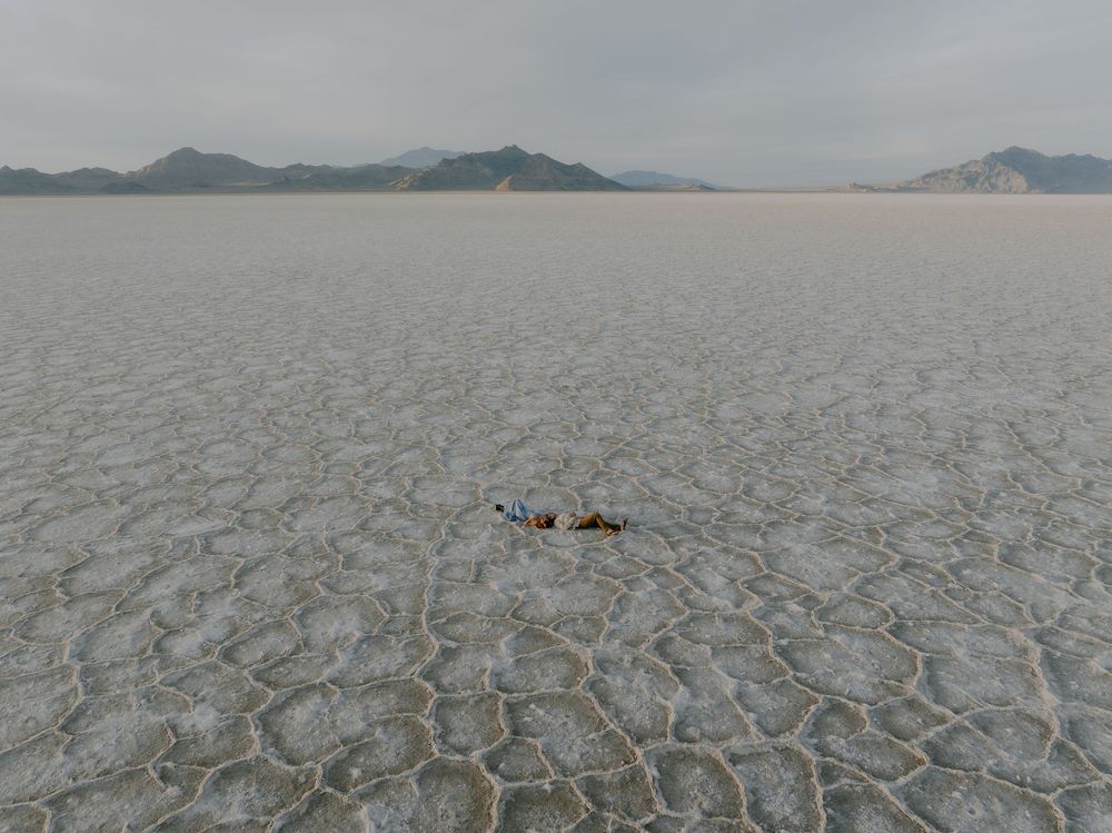 Cracked and parched earth stretches towards distant mountains under an overcast sky in a dry lake bed.