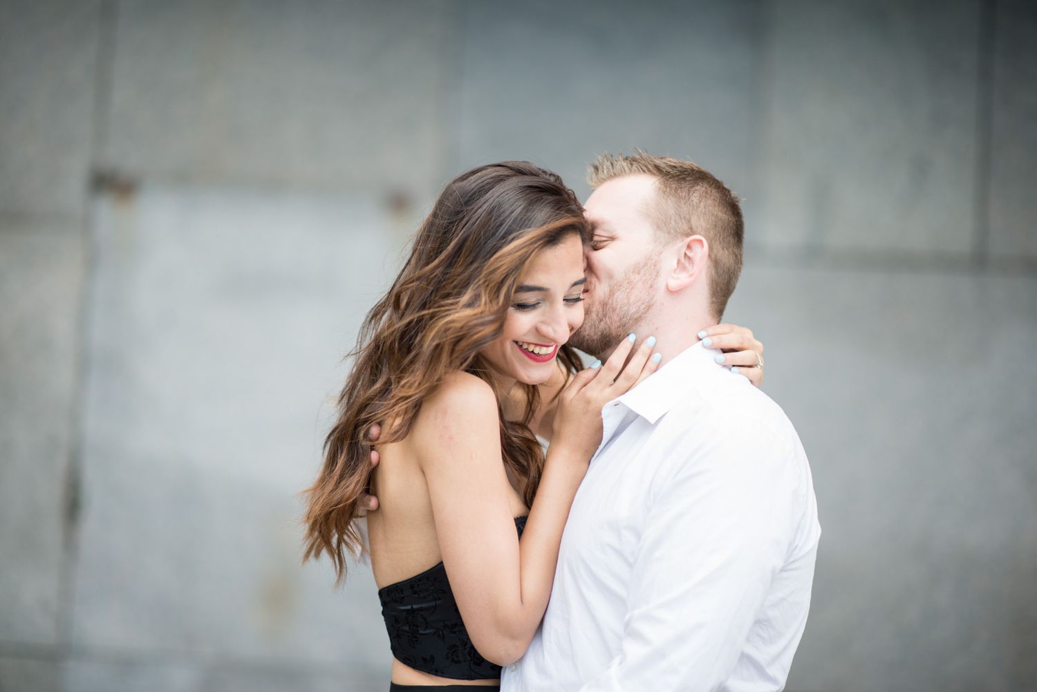 Romantic couple embracing in soft focus against neutral background.