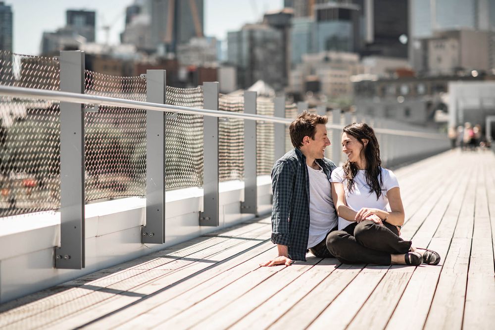 Romantic couple sitting on modern wooden deck with urban skyline backdrop.