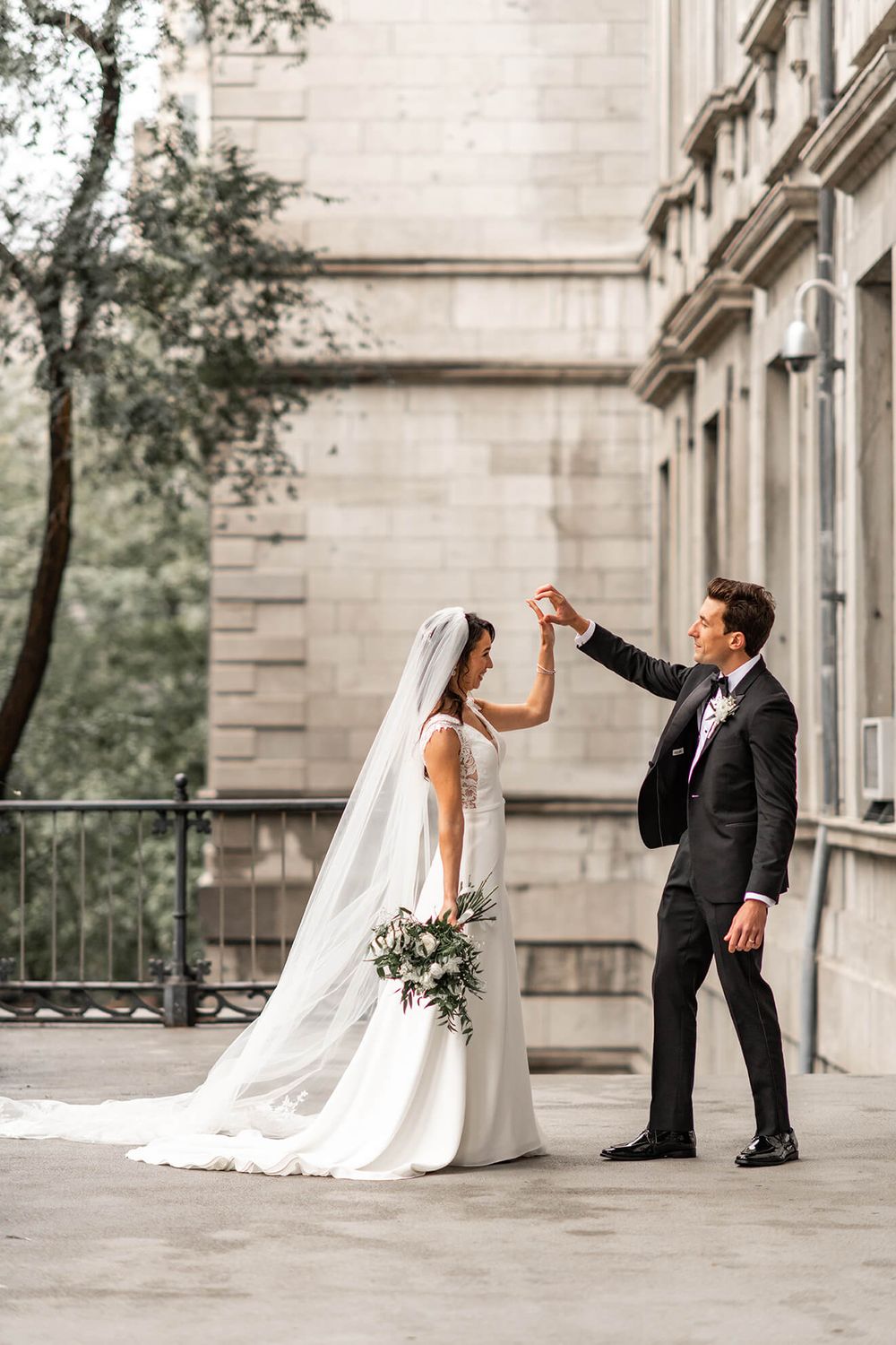 Wedding couple dancing and twirling on stone terrace with classic architecture.