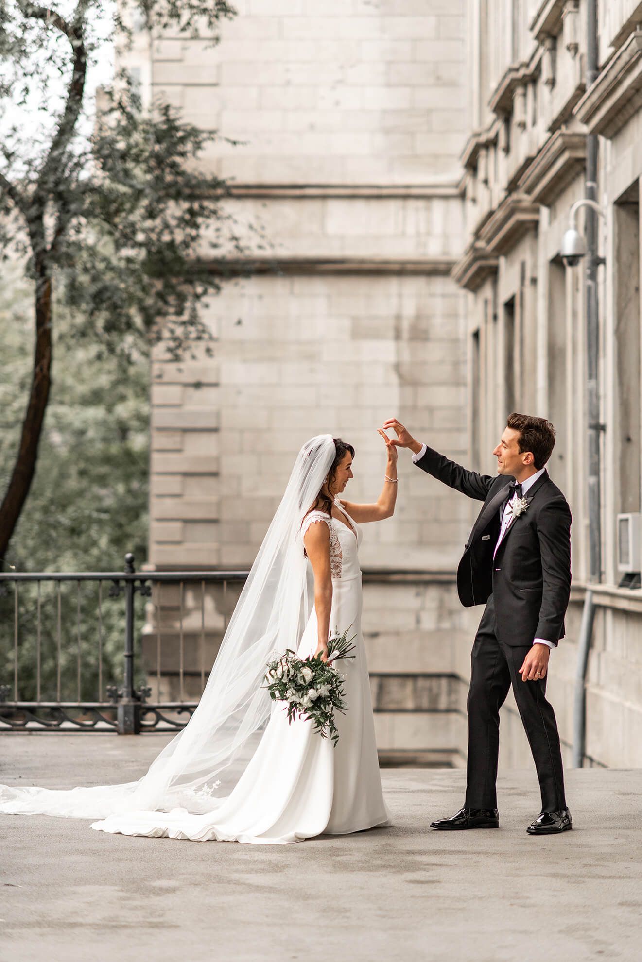 Wedding couple dancing and twirling on stone terrace with classic architecture.