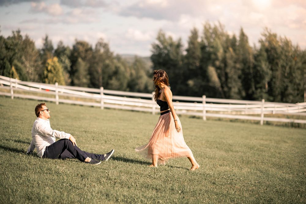 Romantic couple's photoshoot in a grassy field with white fencing at golden hour.