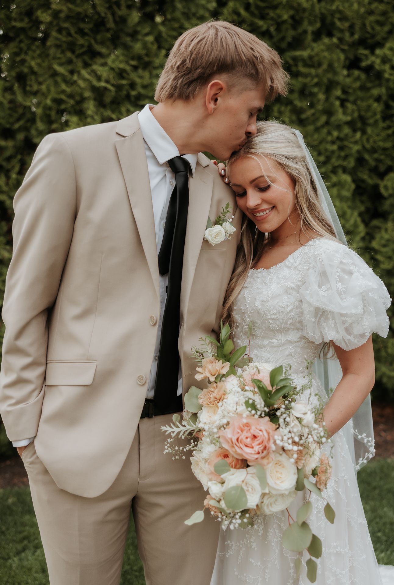 Intimate wedding portrait showing tender moment between bride and groom with blush and white bouquet.