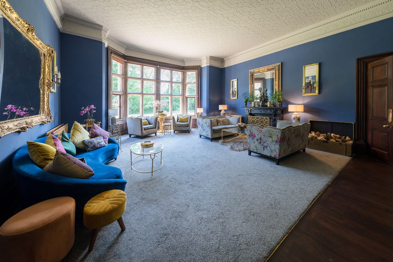 Elegant blue-walled room with ornate gold trim and period furniture in a historic mansion. Ellingham Hall