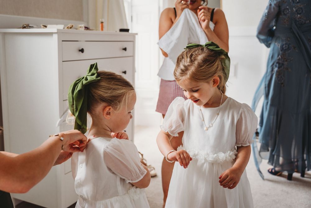 Getting ready sequence showing people helping with wedding dress preparations in a bright room.