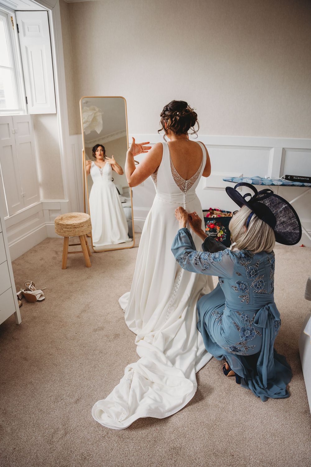 Behind-the-scenes of wedding photography as a dress is captured in a mirror reflection.