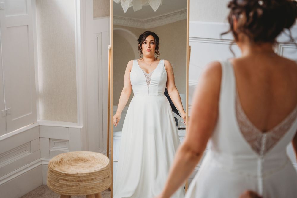 Wedding dress details and preparations in an elegant white room with wainscoting.