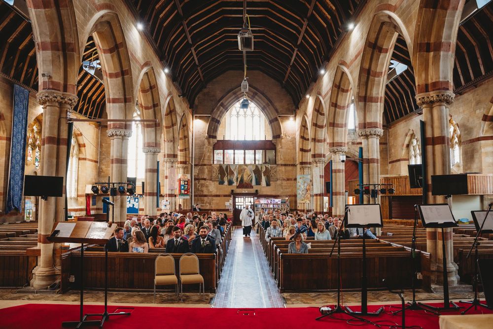 Interior of historic church with wooden beamed ceiling and stone archways during wedding ceremony.