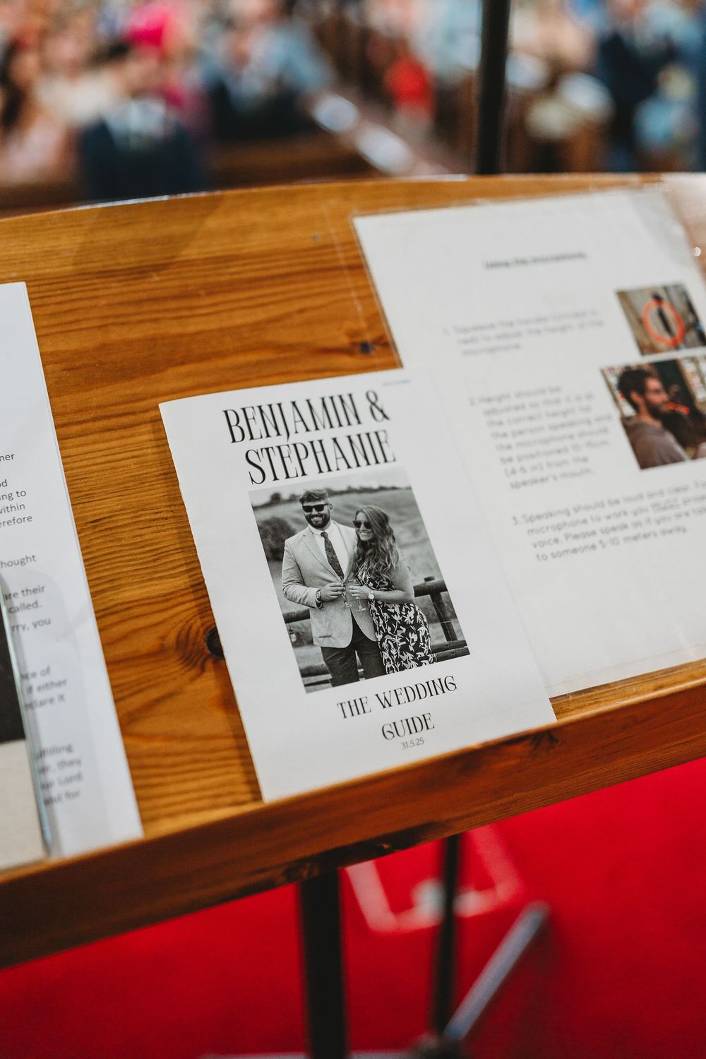 Wedding program cards displayed on wooden table with red accents.
