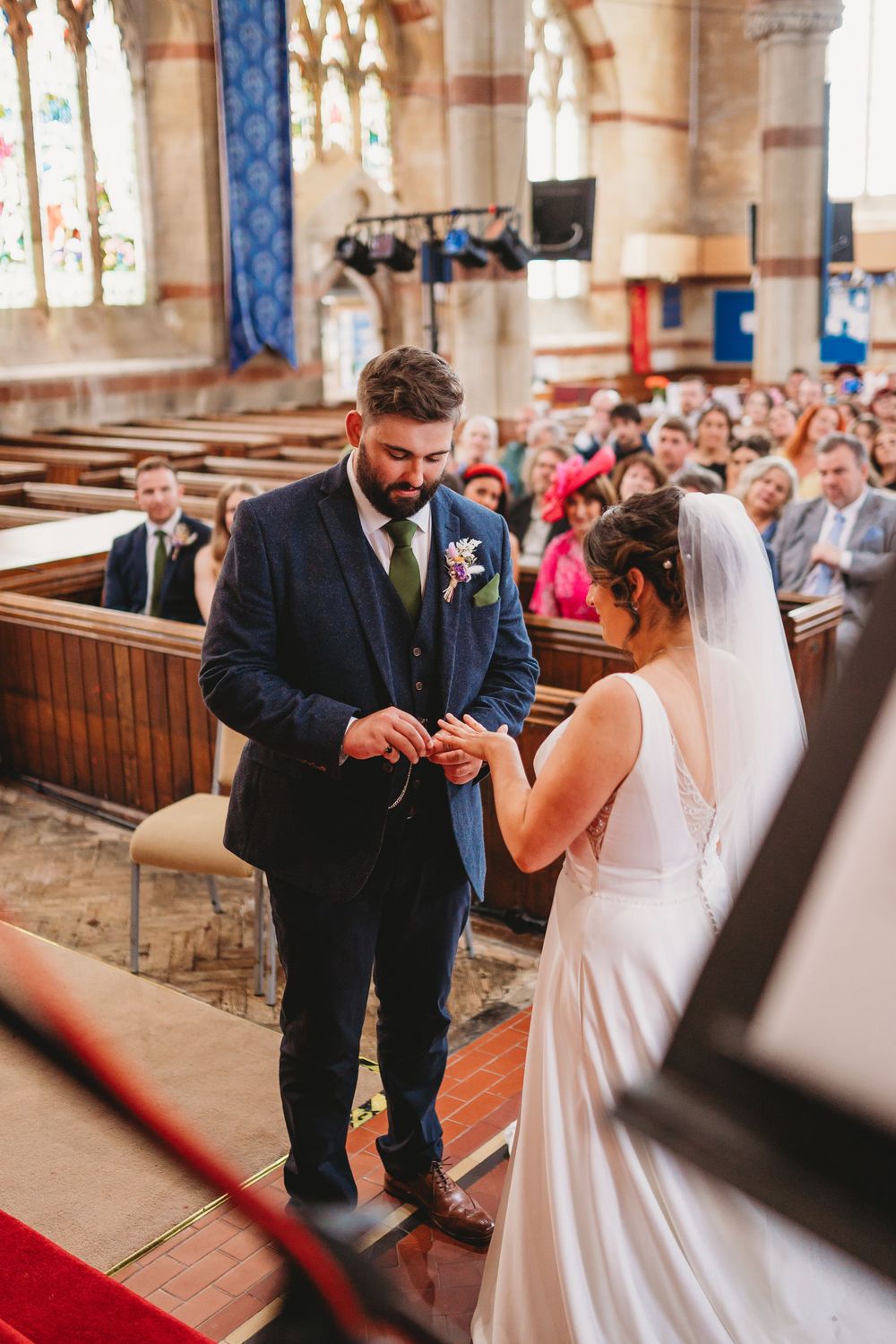 Wedding ceremony in progress inside historic church with stained glass windows.
