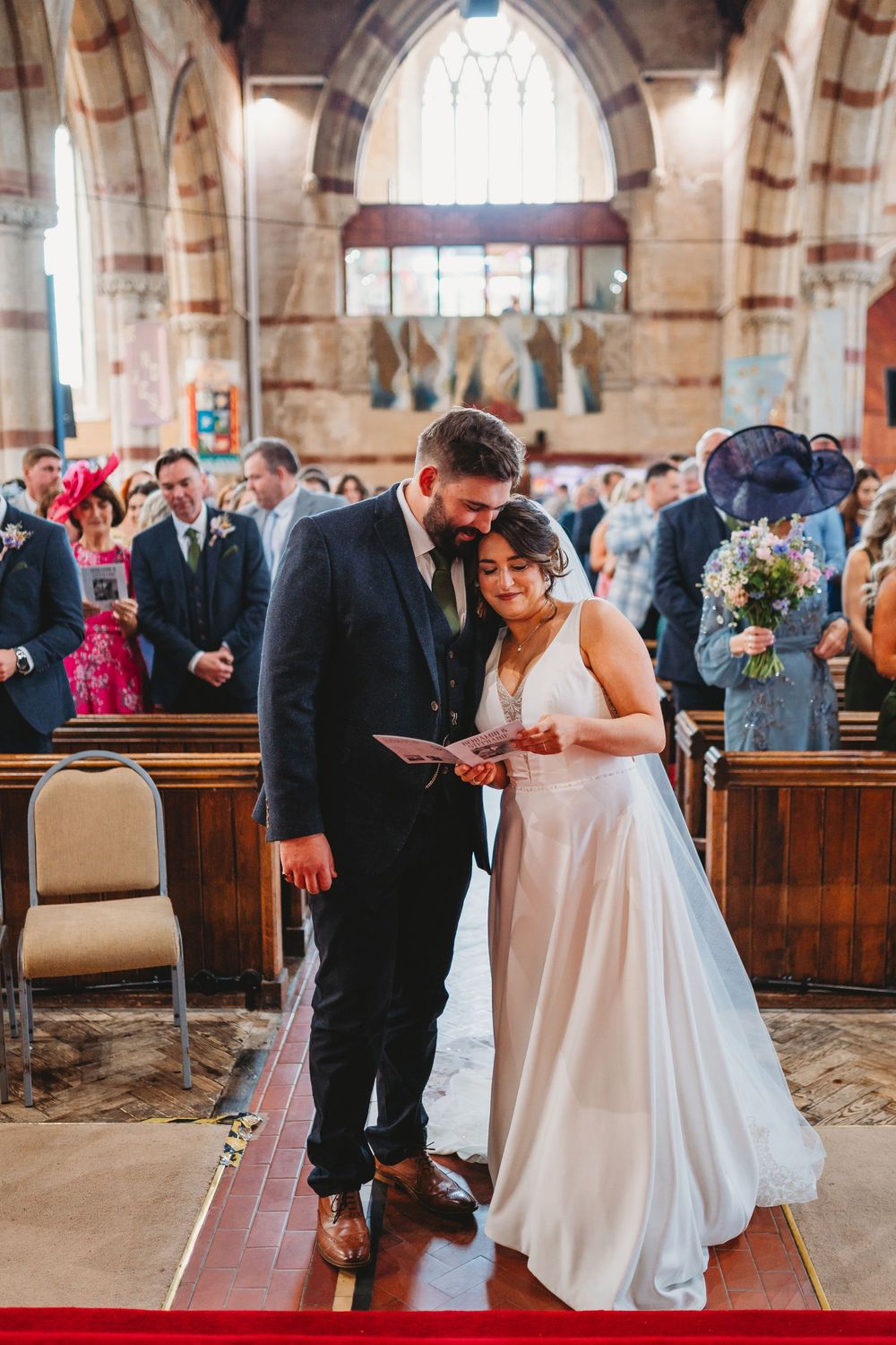 A wedding couple shares an intimate moment during their ceremony in a traditional stone church.