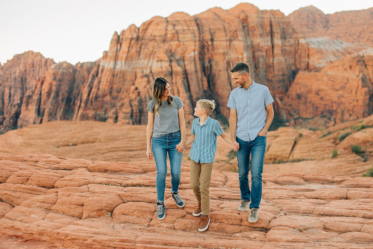A smaller group in coordinated blue outfits stands together on red rock formations in a desert setting.