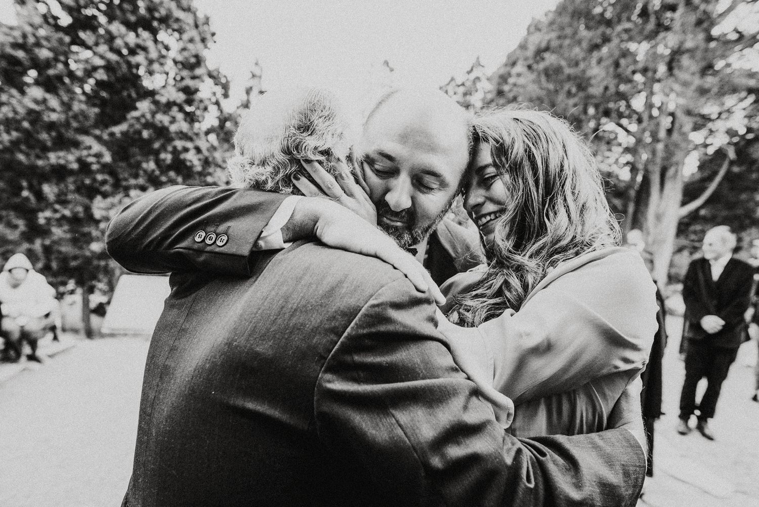 Outdoor black and white wedding photo showing celebration with guests in natural setting.