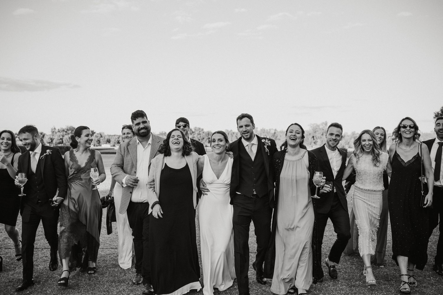 Wedding party members lined up outdoors in black and white formal attire.
