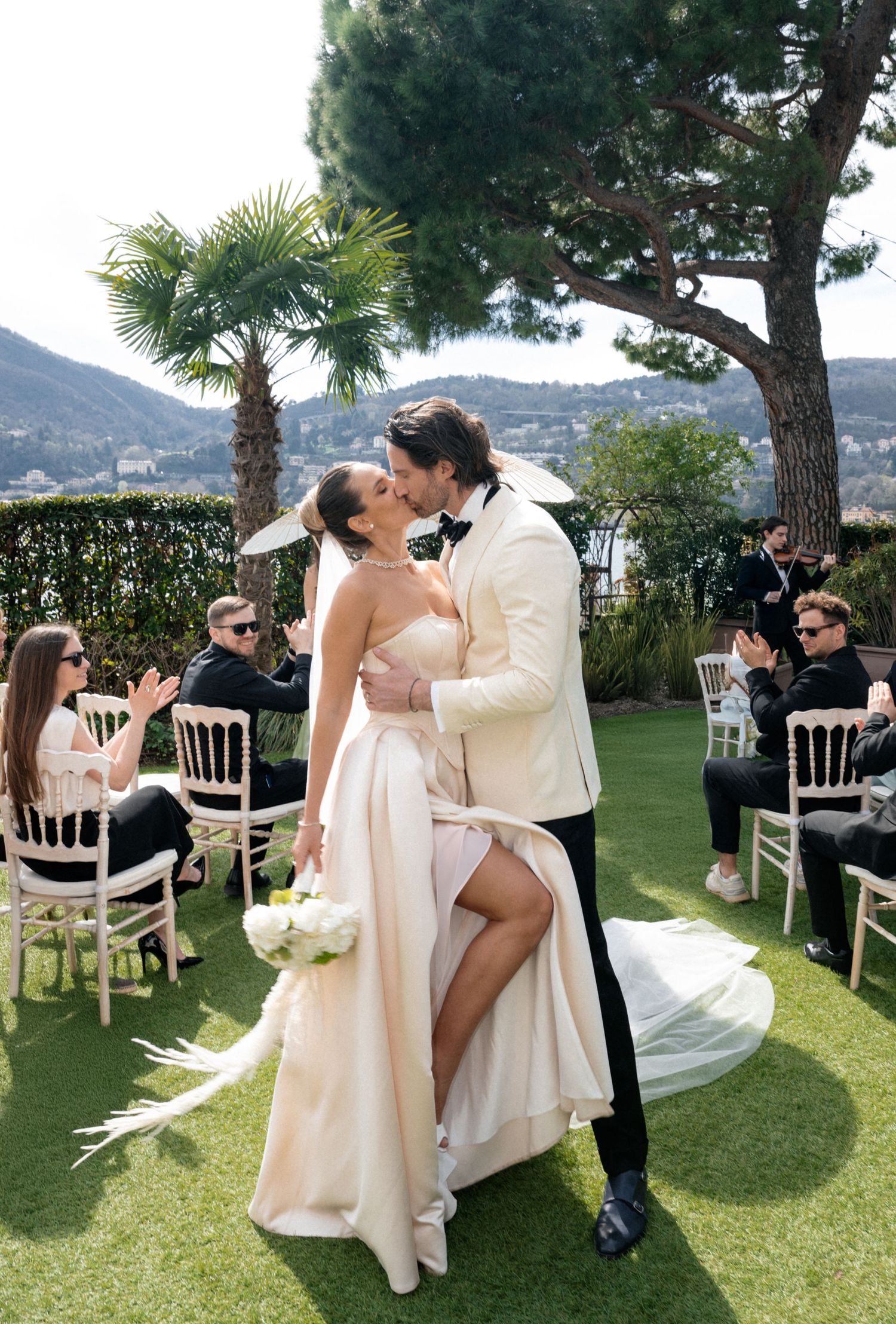 A series of candid wedding photos captured on a grassy lawn overlooking the Mediterranean coastline.