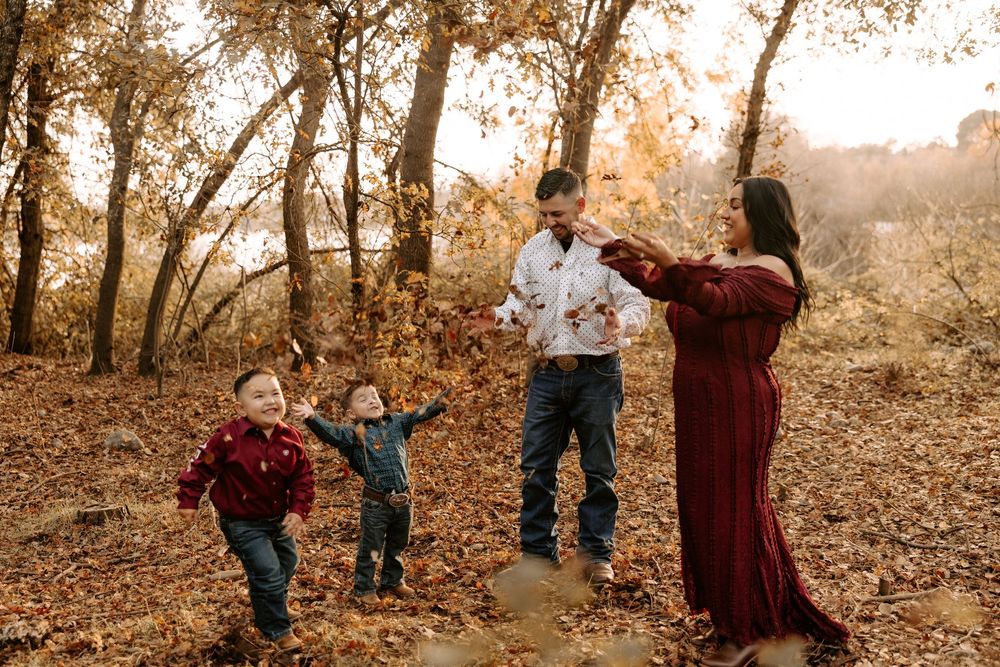 Children playing and running together through a golden autumn forest setting during sunset.