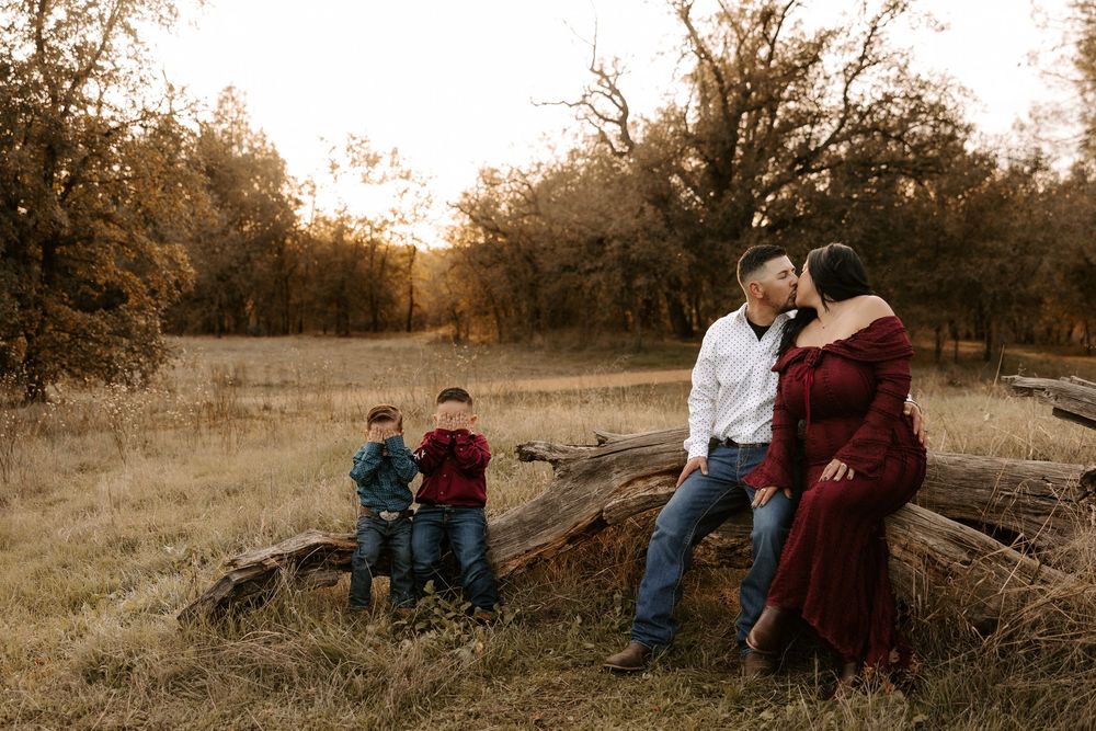 A romantic fall engagement photo session with couples sitting together in a golden sunset field.
