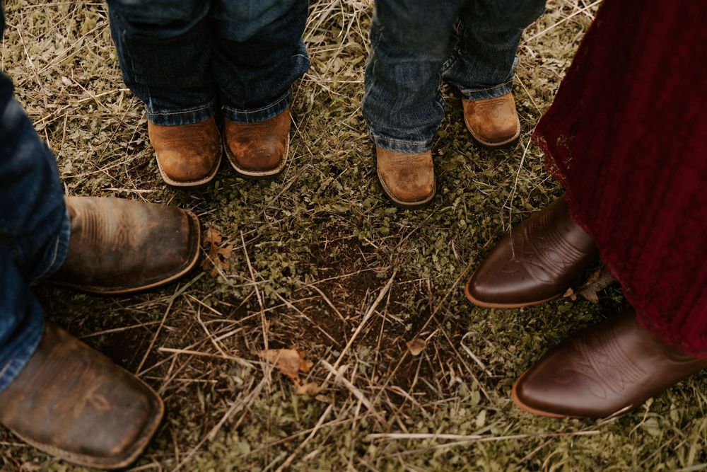 Close-up view of brown leather boots and jeans on fallen leaves in an autumn setting.
