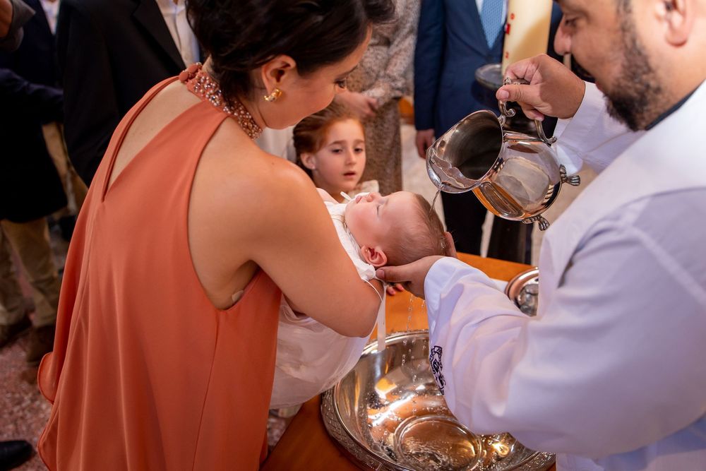 Family gathered around a baby during a church baptism ceremony with priest and relatives present in Guatemala City church