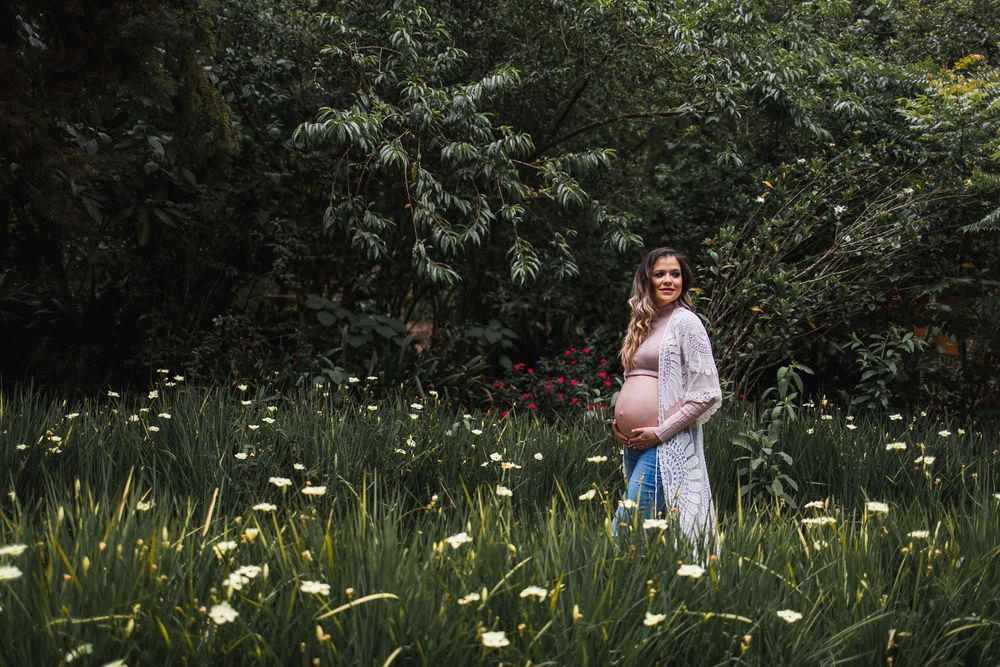 Pregnant woman standing in garden surrounded by greenery during maternity photo session in Guatemala City