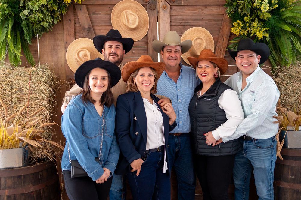 Family group wearing cowboy hats posing at themed party with rustic decor