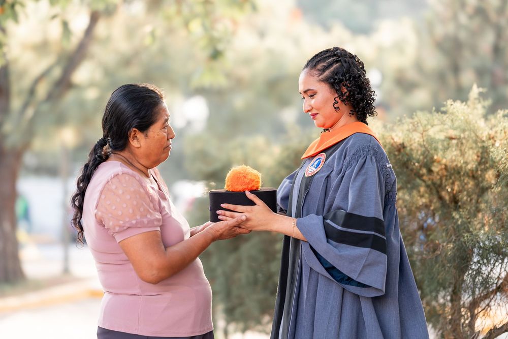 Graduate in cap and gown receiving diploma from mom in Guatemala City.