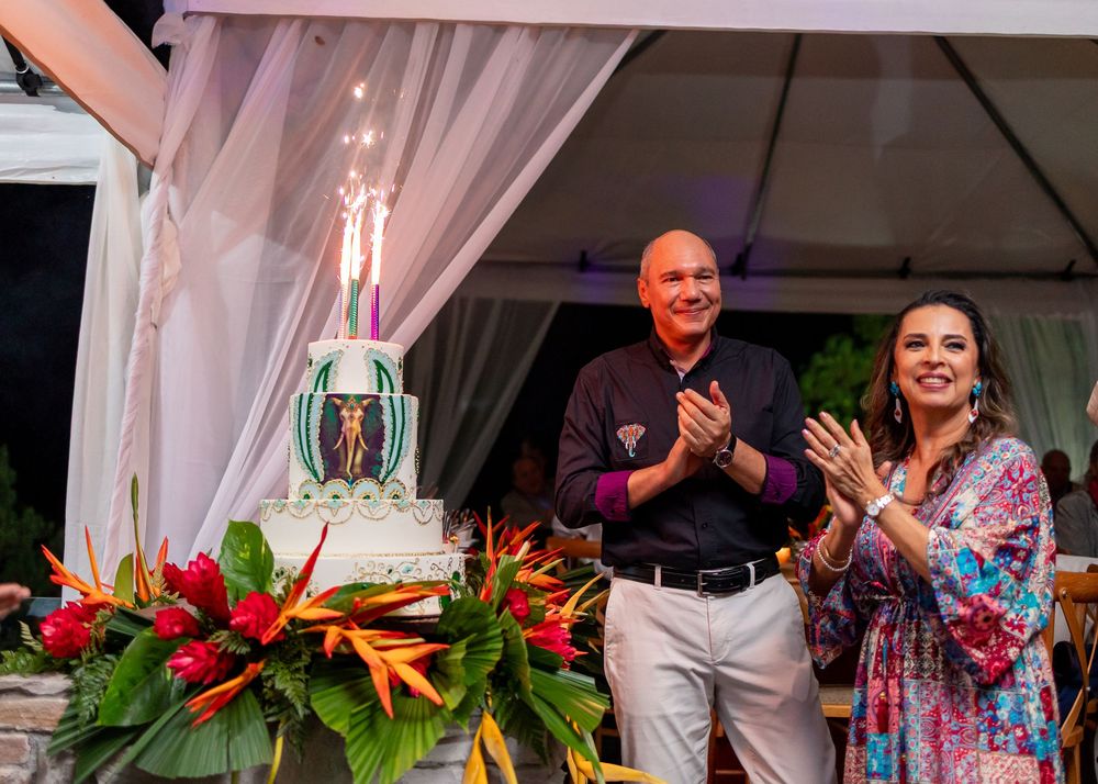 Family celebrating birthday next to decorated cake under outdoor tent