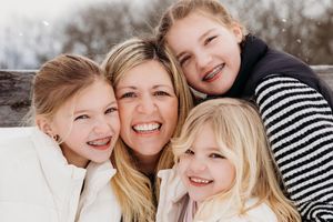 A joyful group embraces while wearing coordinated black and white striped outfits in an outdoor winter setting.