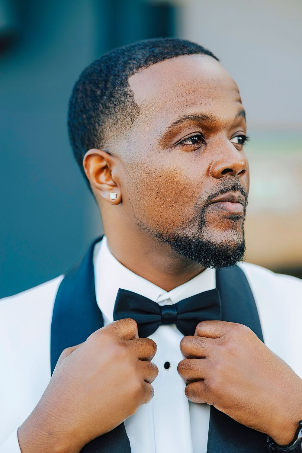 A sequence of close-up shots showing someone adjusting a black bow tie against a crisp white dress shirt.