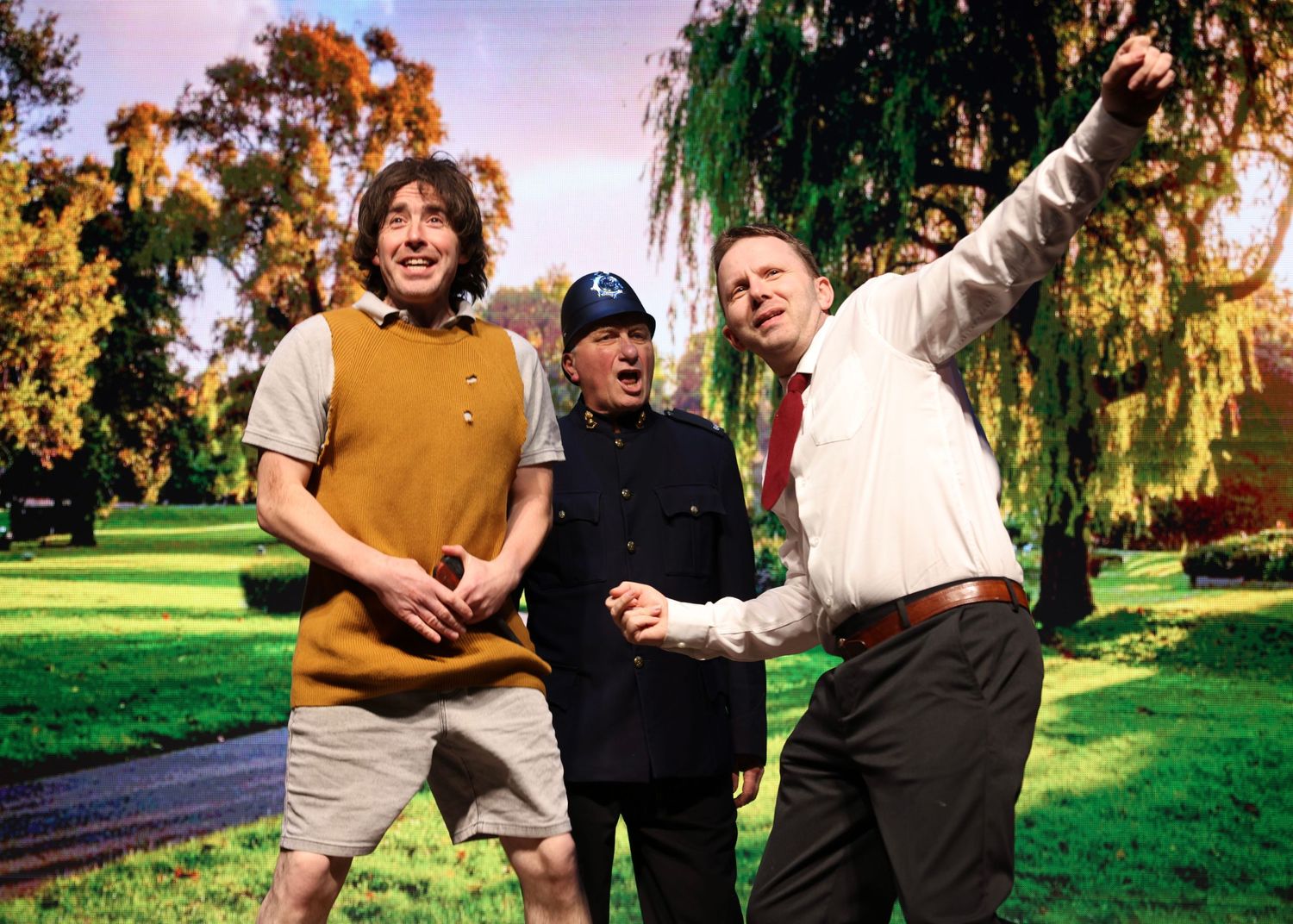 People enjoying a playful moment together in a sunny park with trees in the background.
