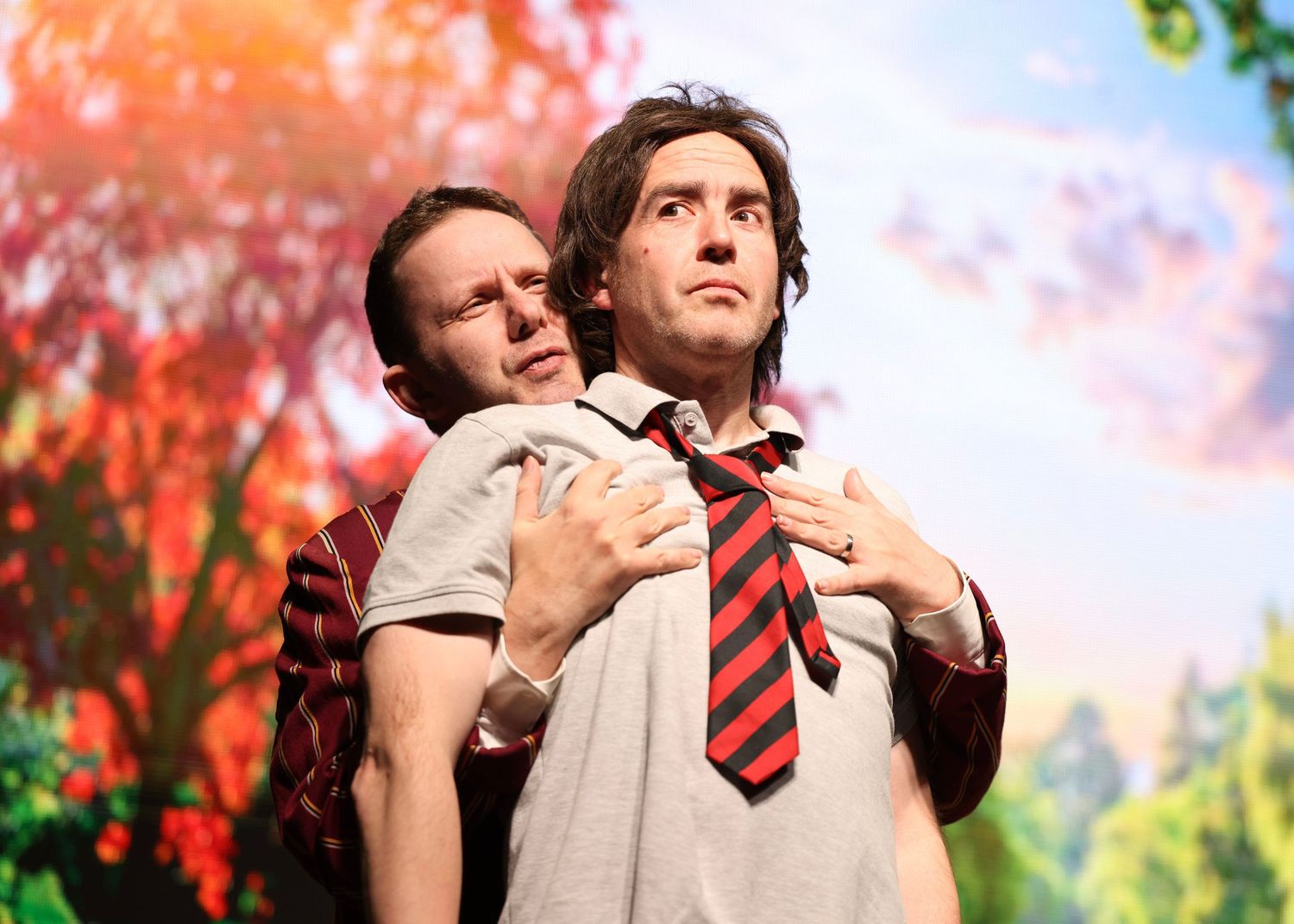 A romantic couple embraces outdoors against vibrant red autumn foliage in a tender moment.