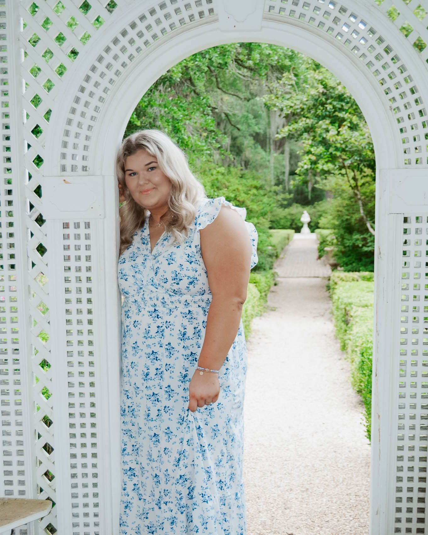 A light blue floral dress photographed in a garden setting with white lattice archways.