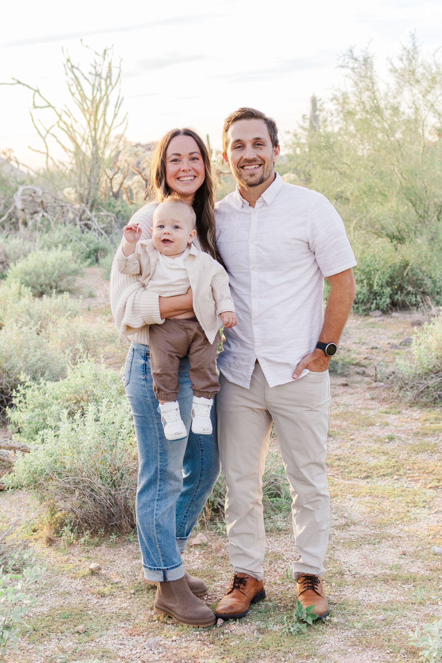 mom holding her infant son smiling in the middle of the desert