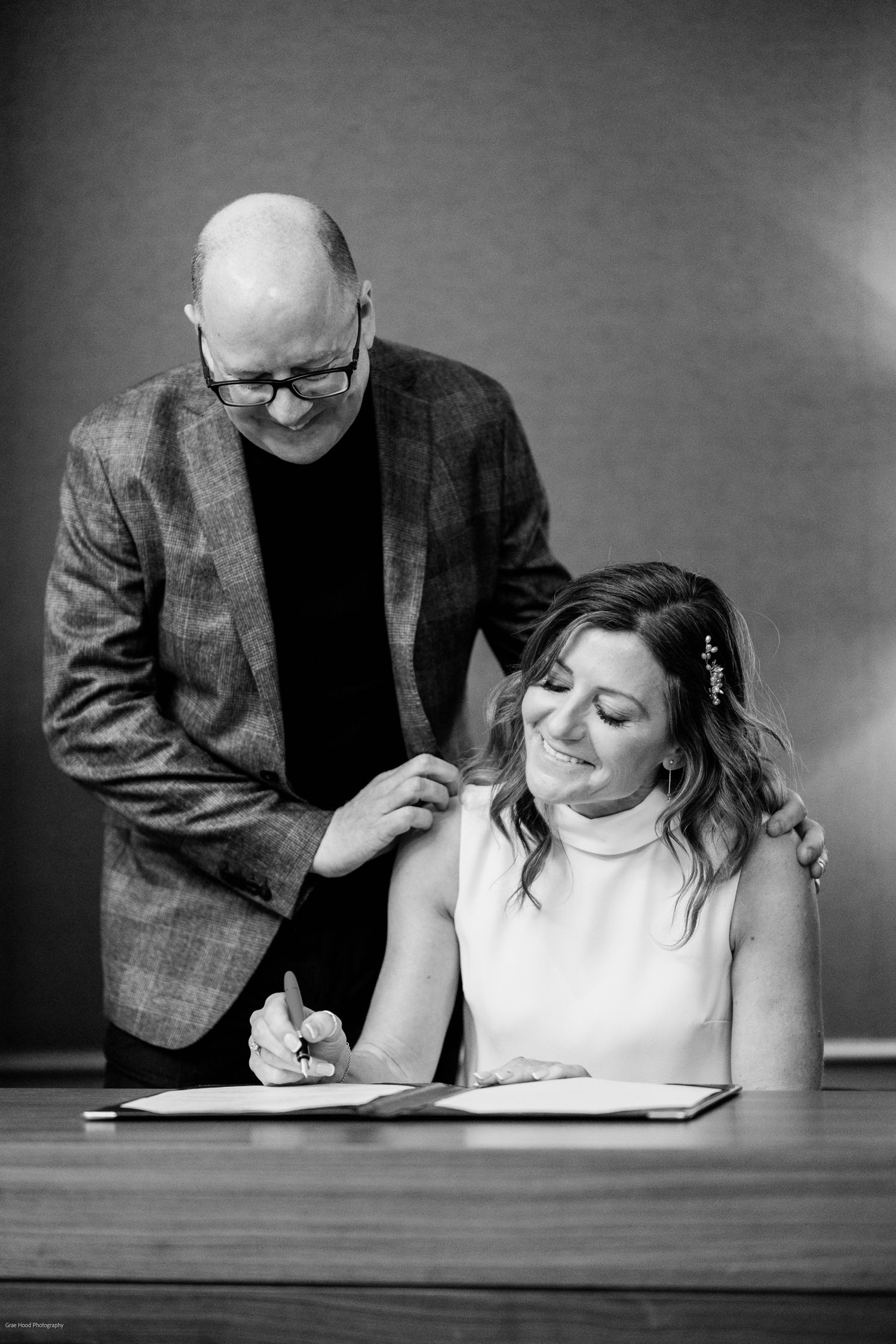 Black and white photo sequence showing two people at a desk collaborating on paperwork in a professional setting.